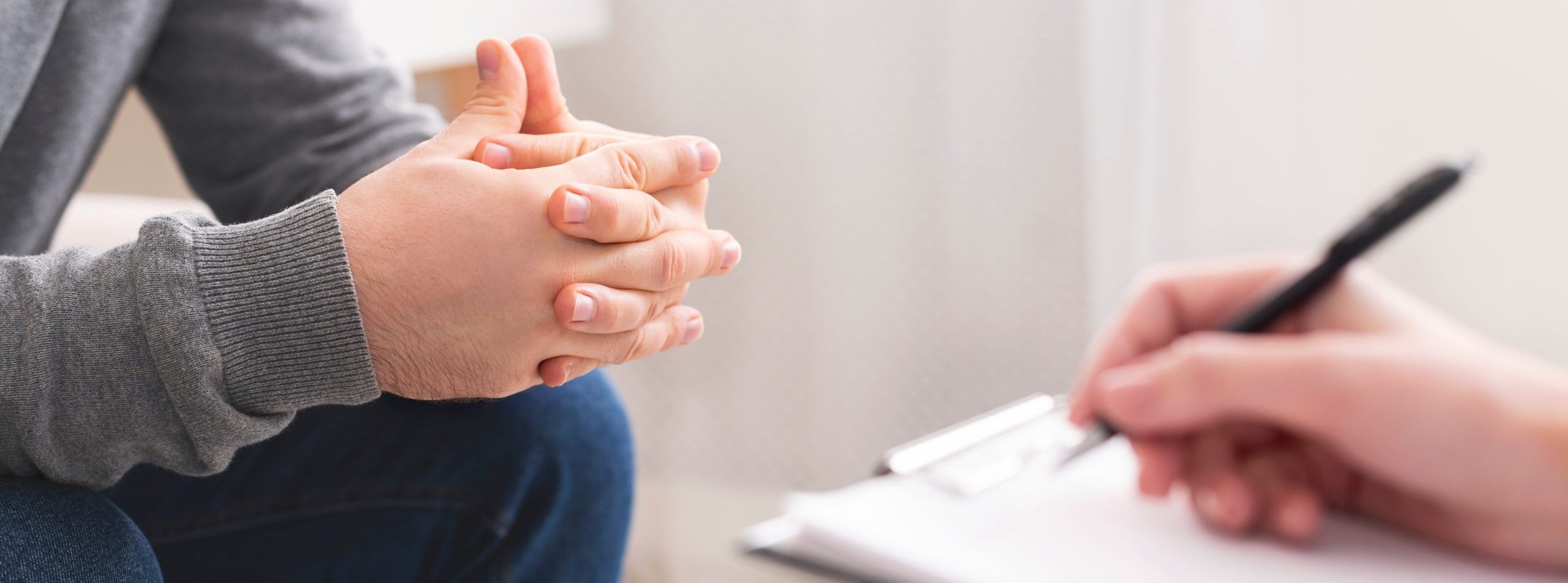 Therapist writing notes during counseling session with single man